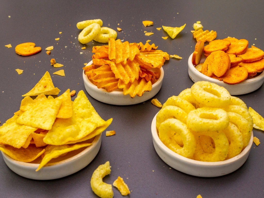 Four small bowls filled with different kinds of junk food