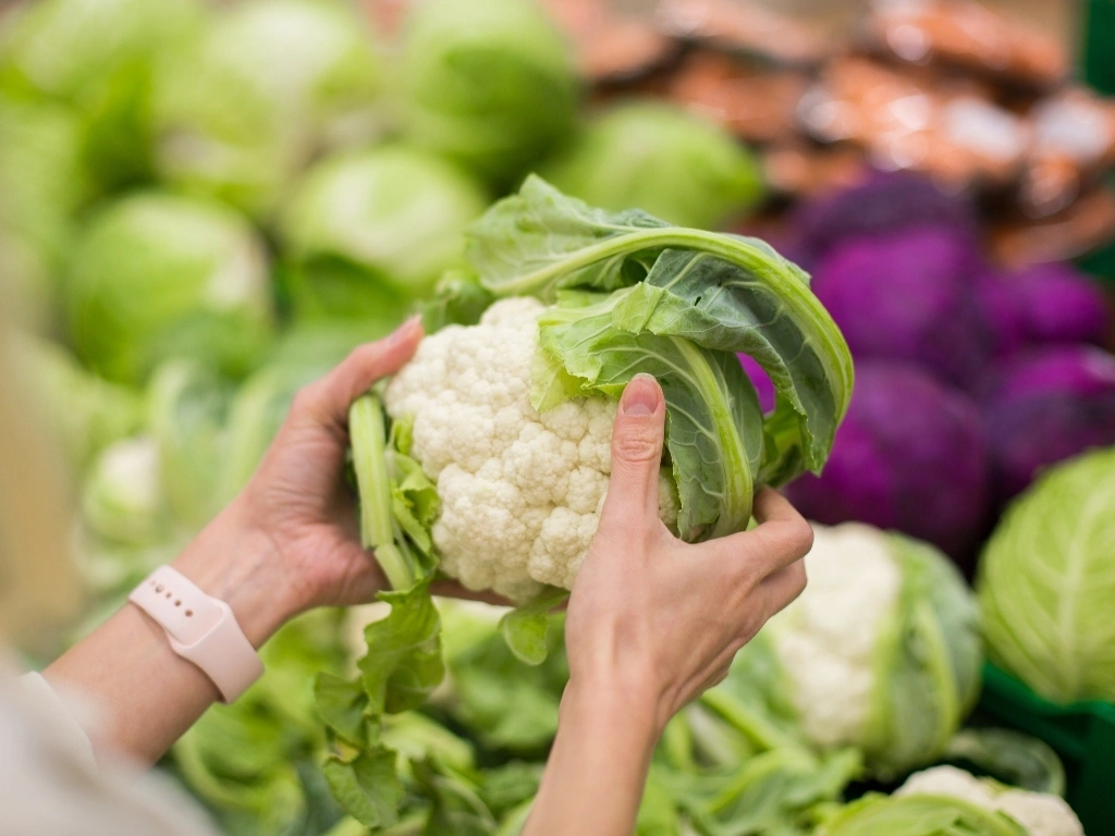 Woman holding a cauliflower in a grocery store