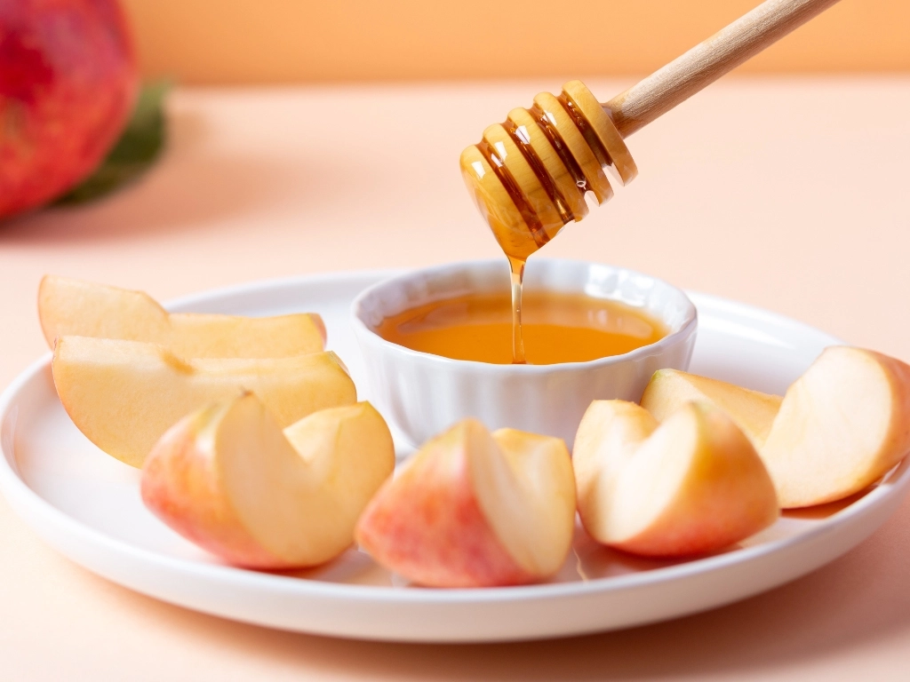 Plate of sliced apples served with a small bowl of honey