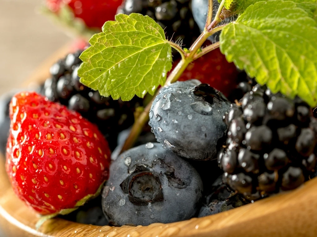 Strawberries, blackberries, and blueberries in a wooden bowl