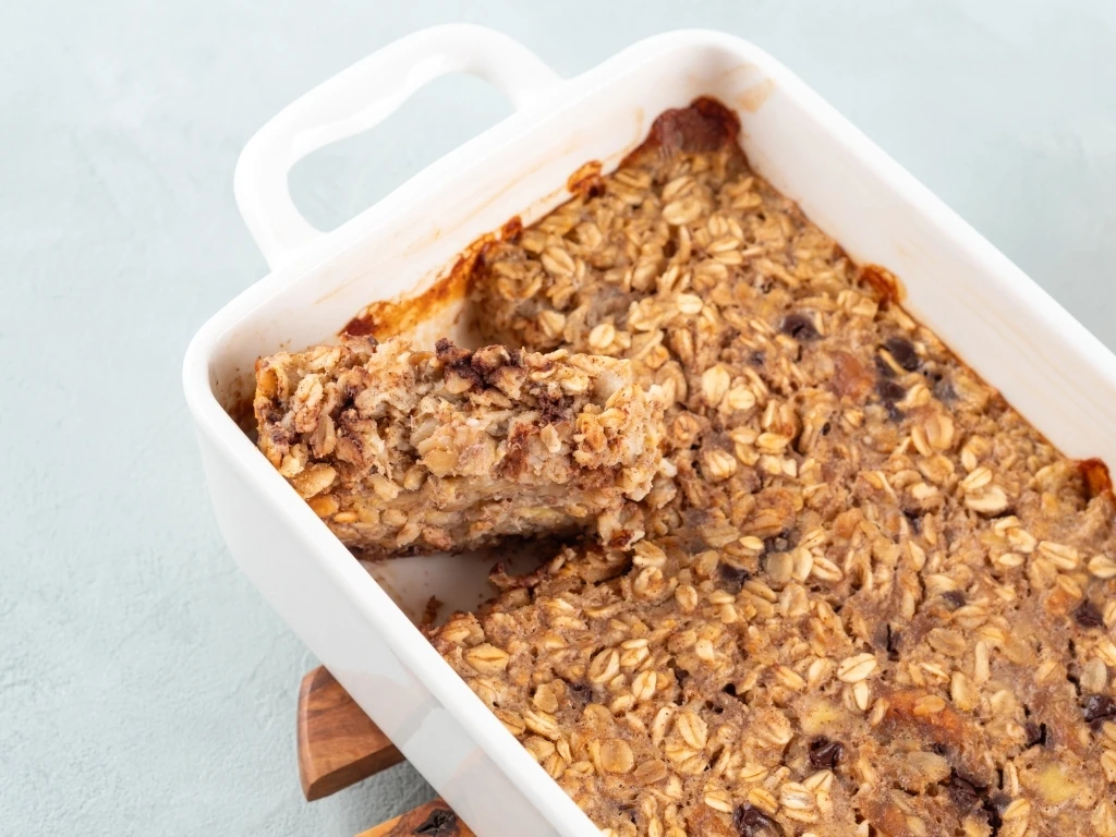 Vegan oatmeal banana cake in white baking pan on turquoise
