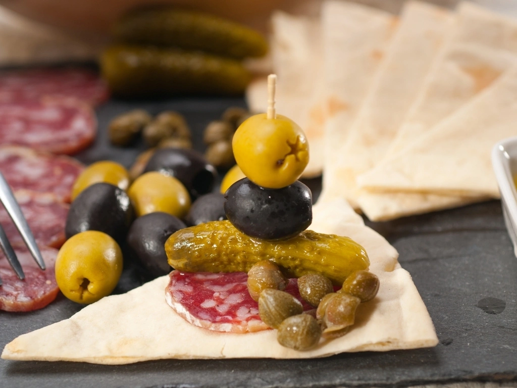 Olives, pickles, and salami on flatbread 