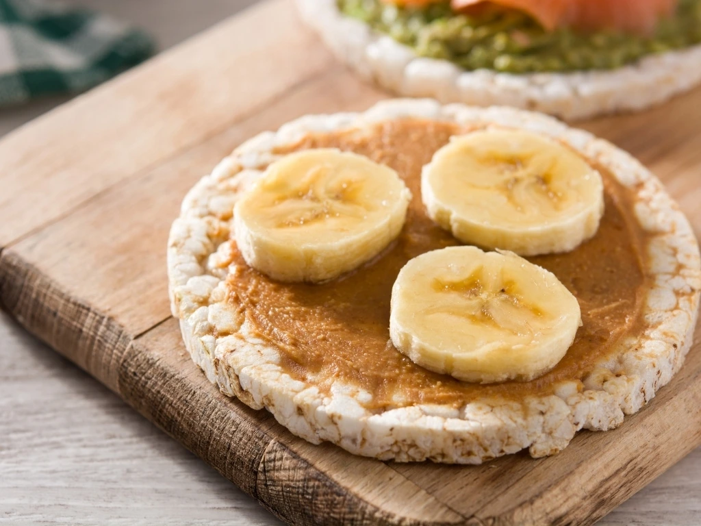 Rice cake with peanut butter and banana on a wooden board