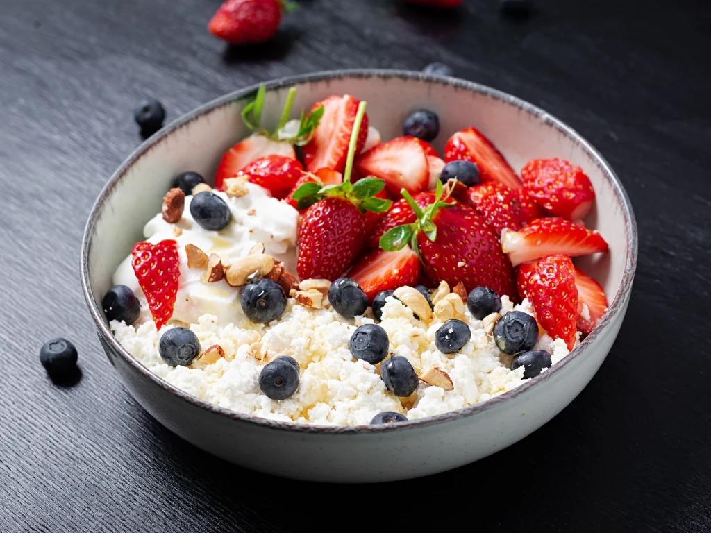 Bowl of cottage cheese topped with fresh berries and chopped almonds