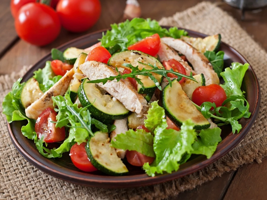 Plate of chicken salad with mixed greens, cucumbers, and tomatoes