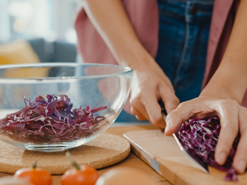 Woman transferring newly chopped red cabbage into a bowl 