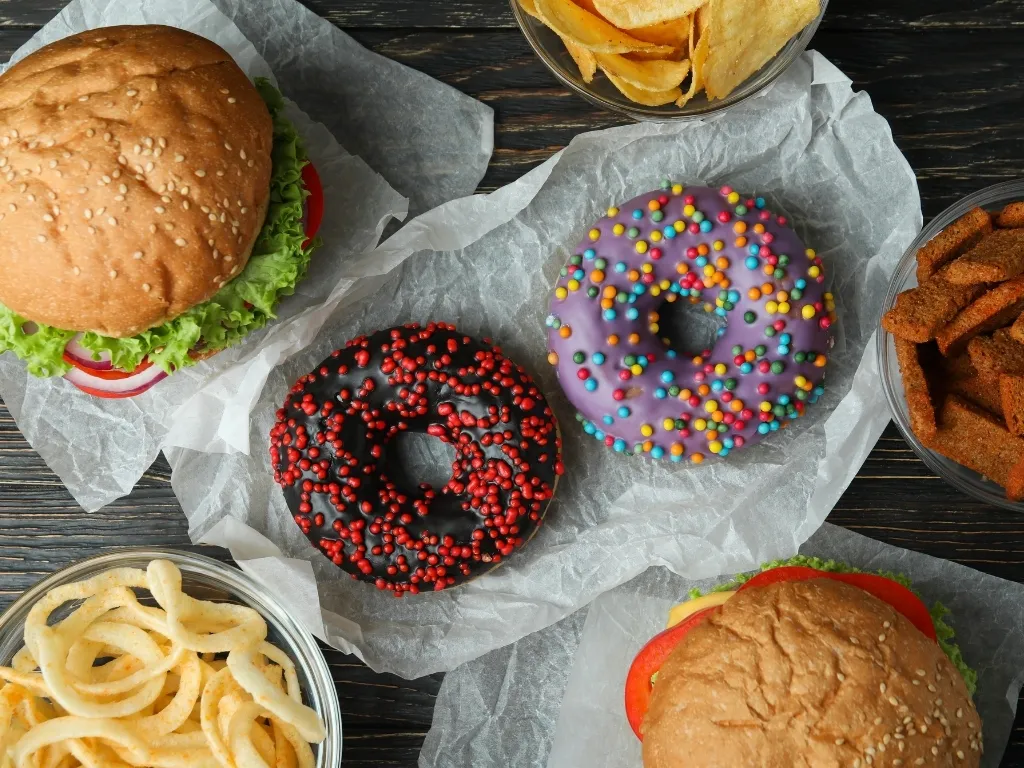 A variety of fast food items, including burgers, fries, and donuts, on a table