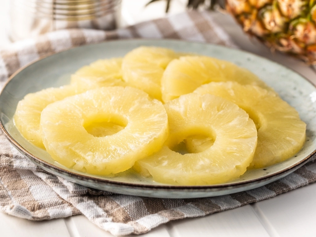 Canned sliced pineapple fruit on plate.