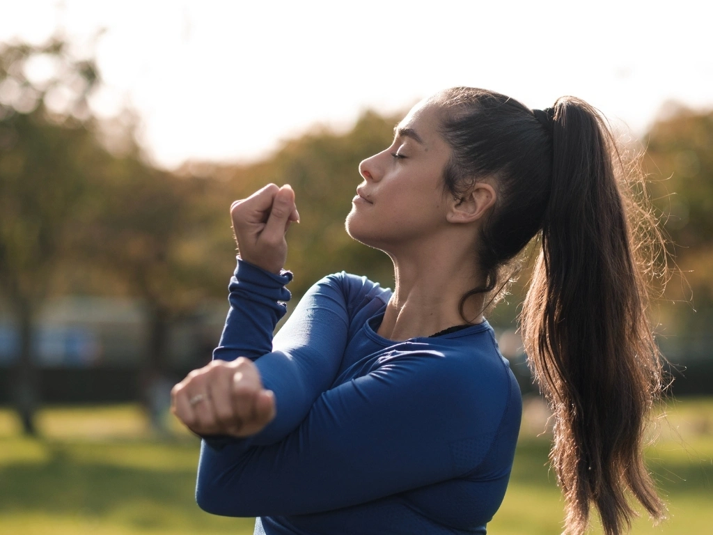 Woman stretching in a park with eyes closed
