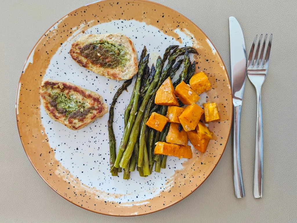 Plate of grilled chicken with roasted asparagus and sweet potato cubes