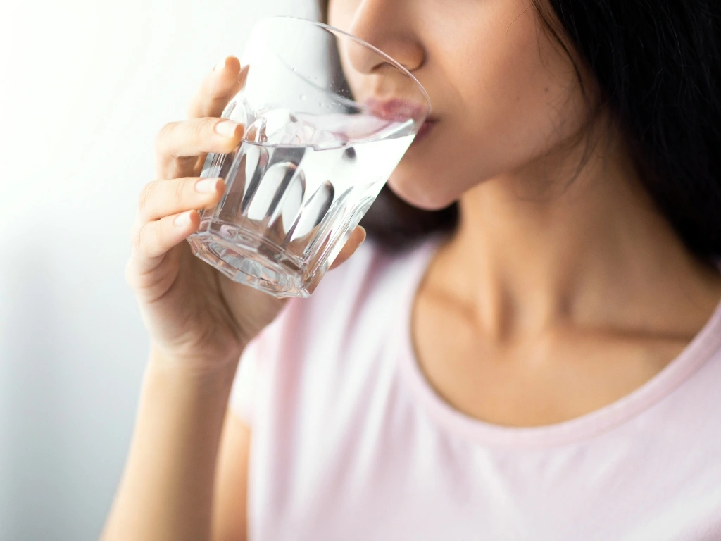 Woman in pink drinking a glass of water