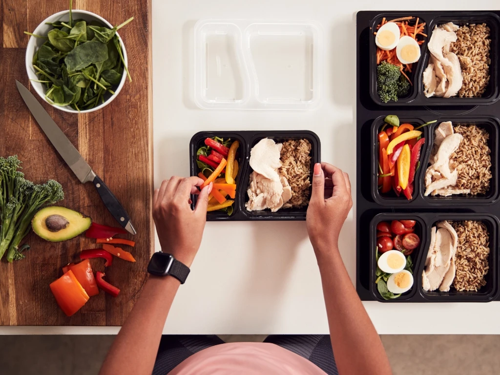 Person preparing well-portioned meals in the kitchen