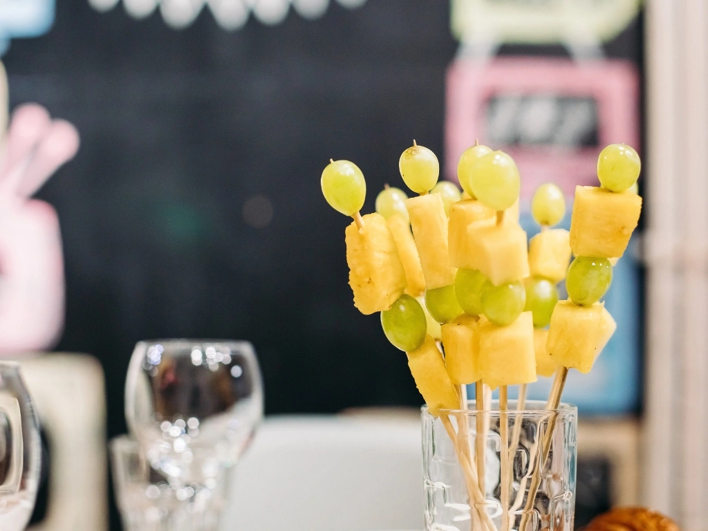 Glass full of skewered green grapes and pineapple cubes