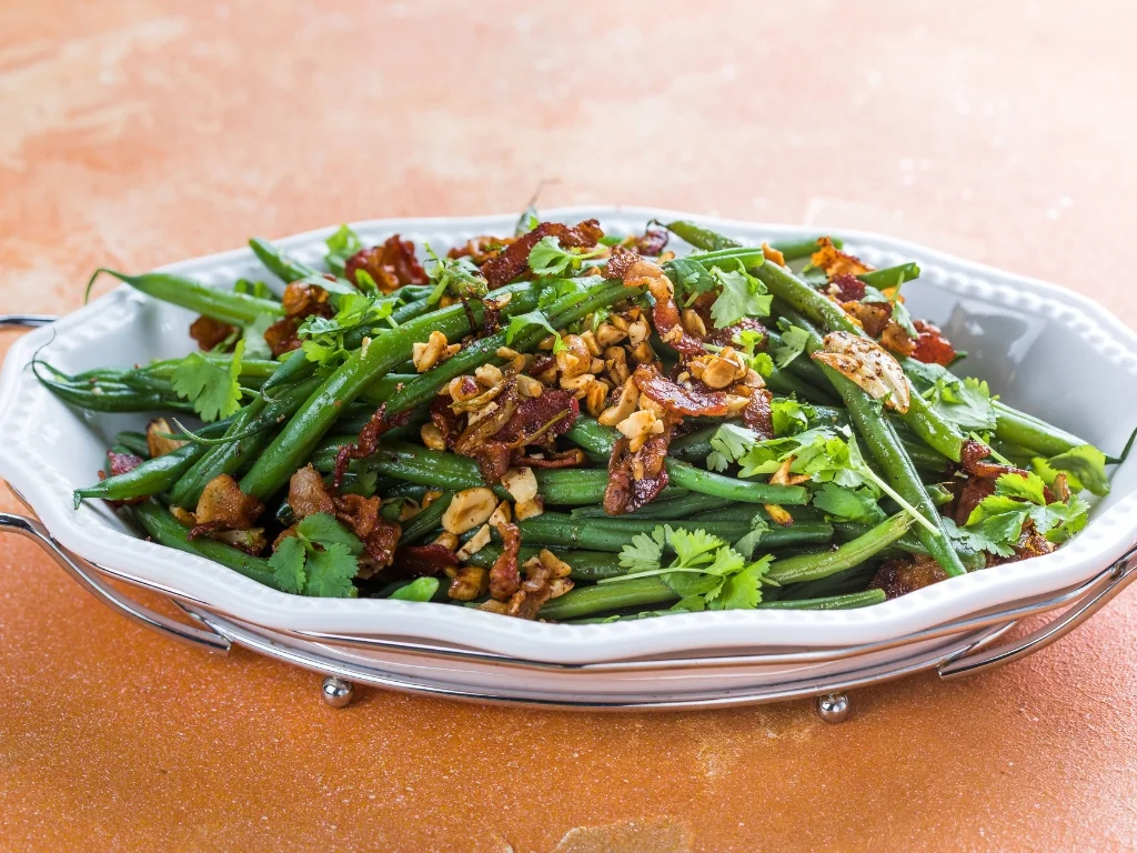 Plate of green beans with nuts and dried cranberries, served with herbs