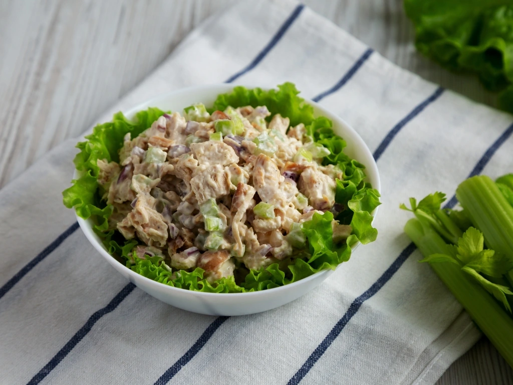Bowl of tuna salad with plain yogurt, celery, and lettuce, served next to fresh celery and lettuce