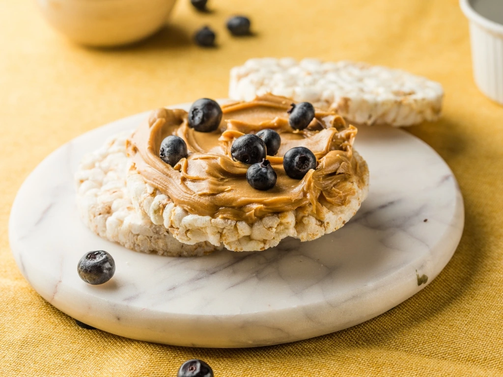 Rice cakes topped with peanut butter and blueberries, served on a round marble plate