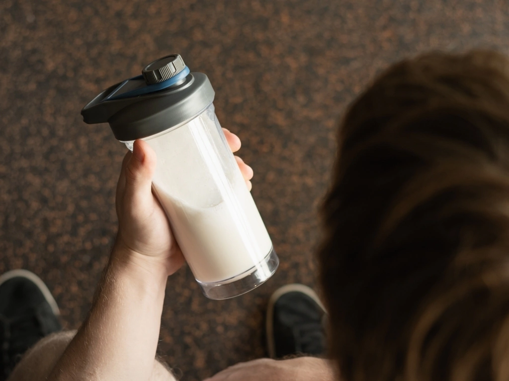 Person holding a protein drink shaker with liquid inside