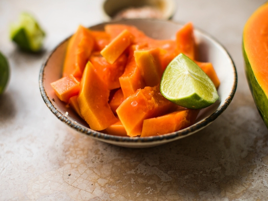 Slices of papaya served on a small plate with lime and salt
