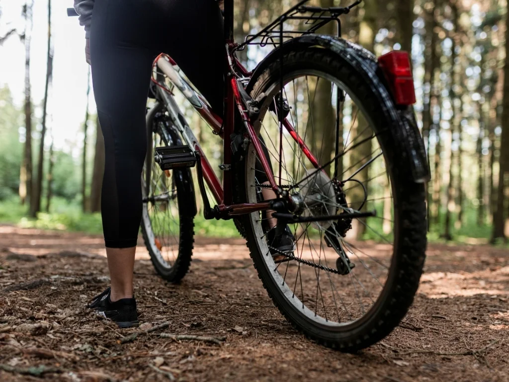 Close-up of a person mounting a bicycle in a forest