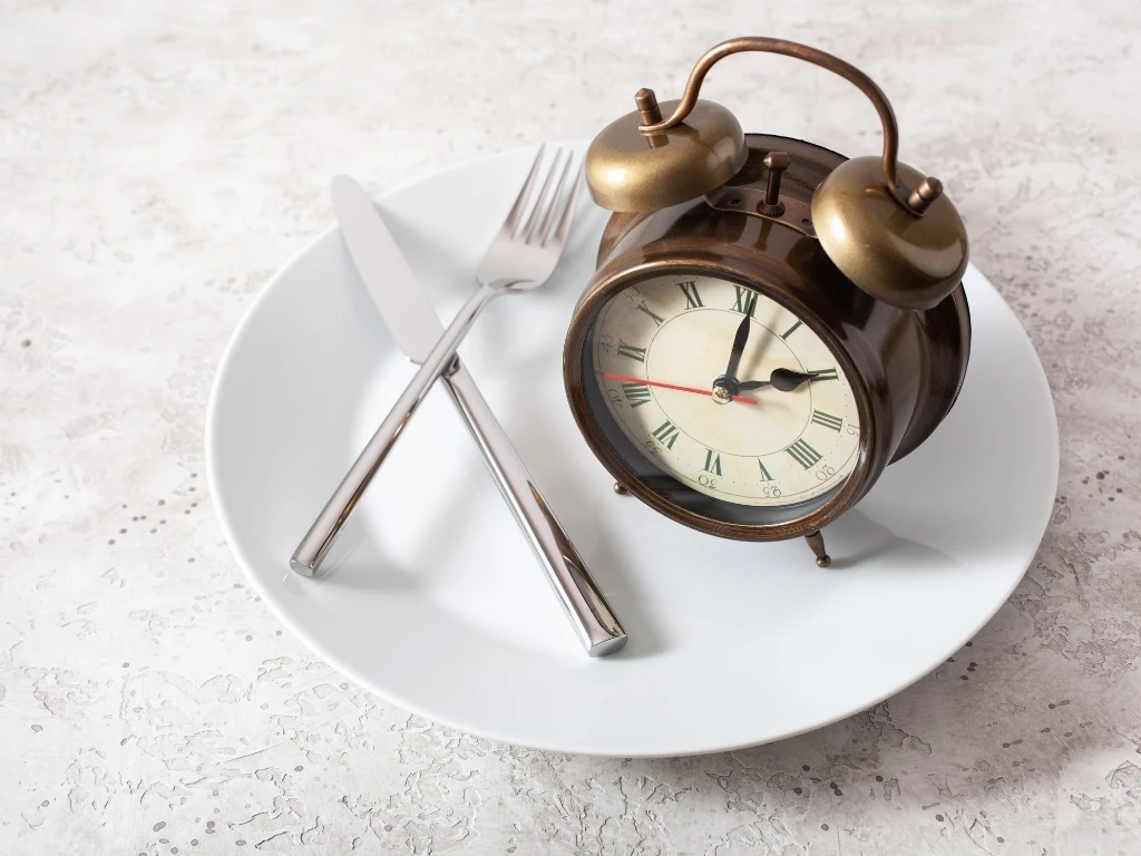 An alarm clock and utensils resting on an empty plat