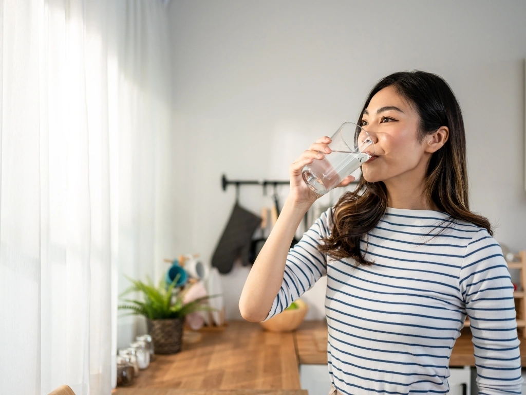 Young woman drinking a glass of water at home