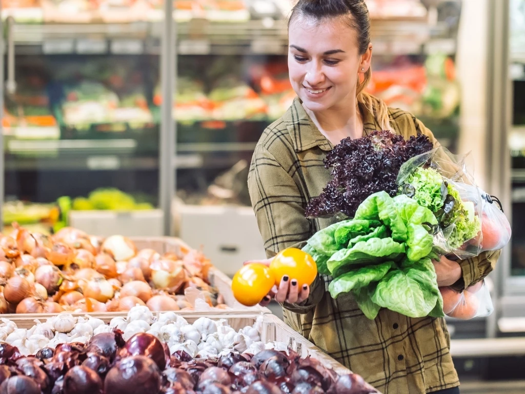Beautiful young woman shopping in a supermarket and buying organic vegetables