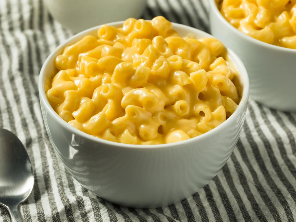 Bowls of mac and cheese next to a spoon
