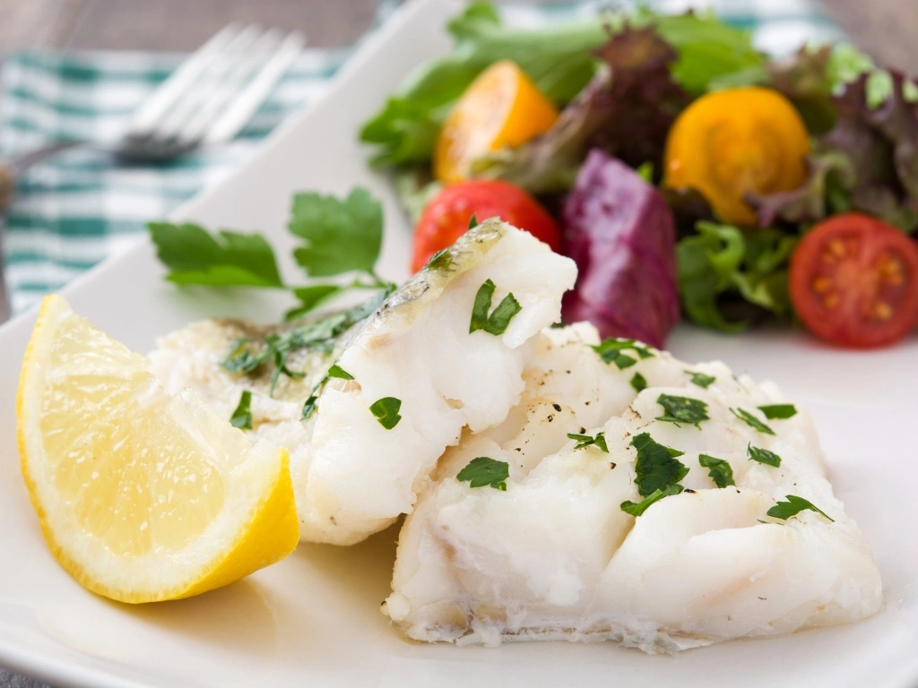 Baked cod served with garden vegetables and a lemon wedge