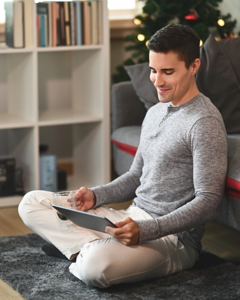 Young man sitting in living room and using digital tablet.