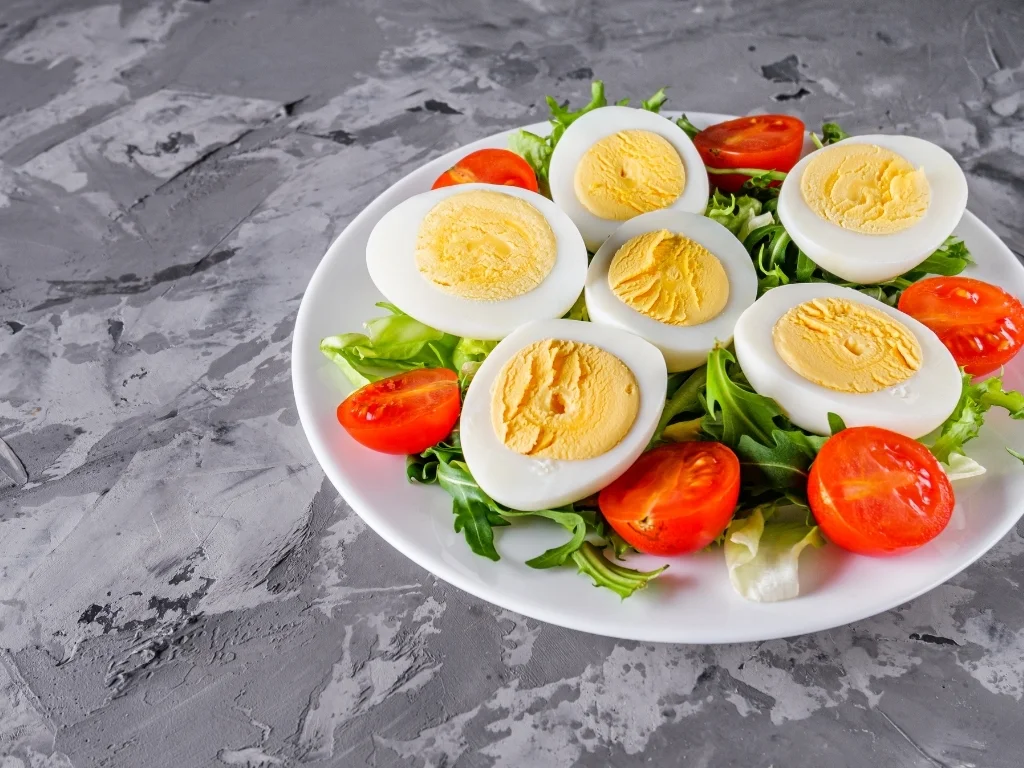 Sliced hard-boiled eggs and cherry tomatoes served on top of some greens