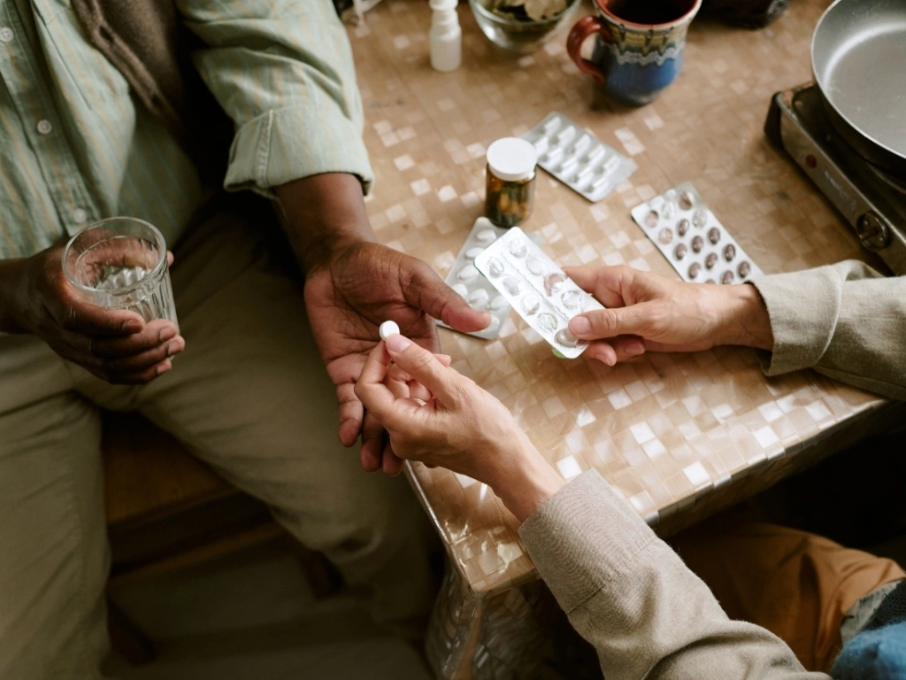 Person giving medicine to another individual