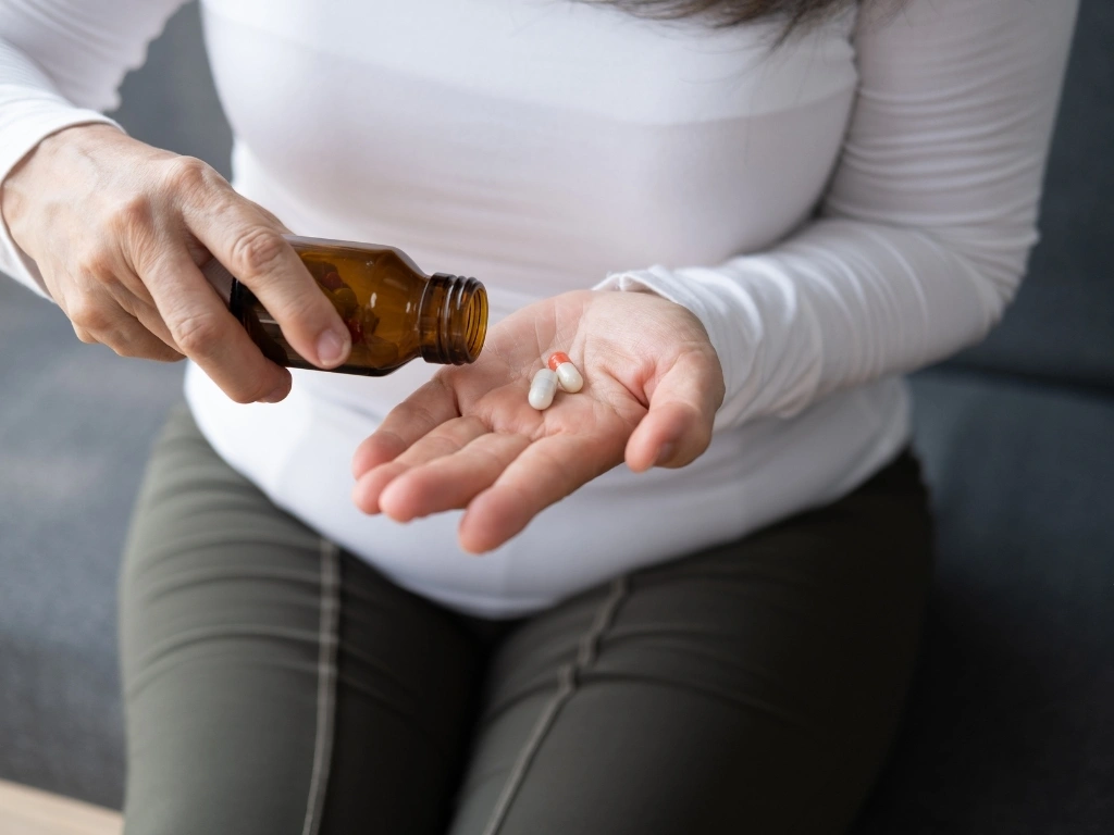 Woman pouring capsules from an amber medicine bottle