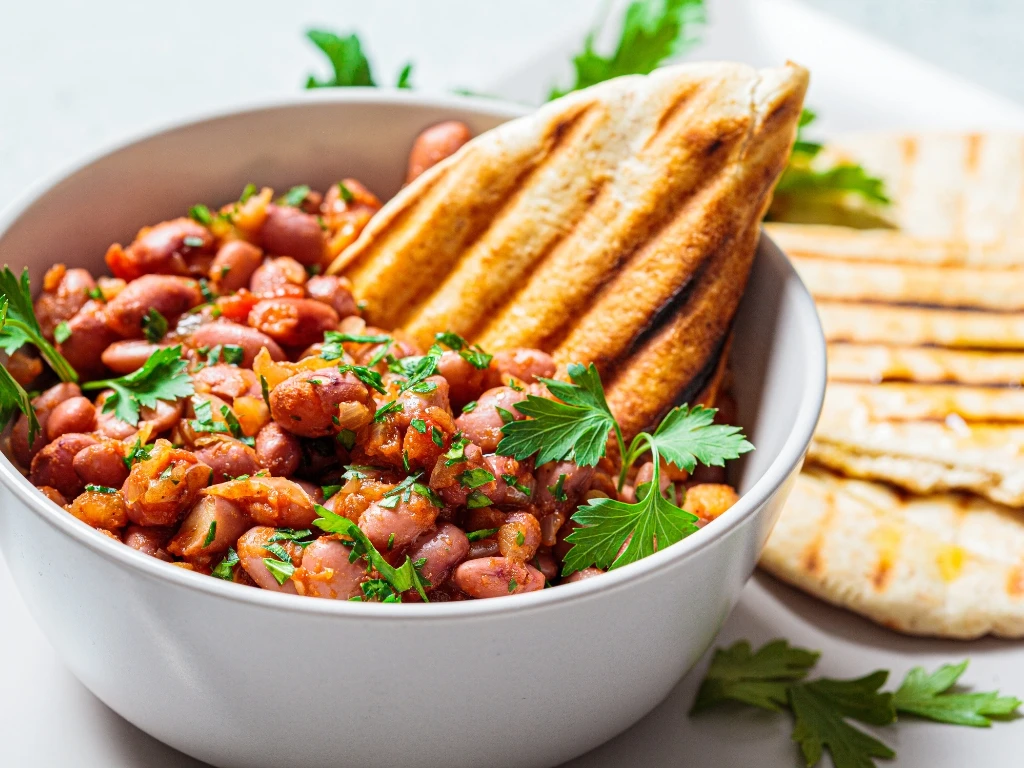 Bowl of savory squash and white bean stew garnished with green onions, served with flatbread