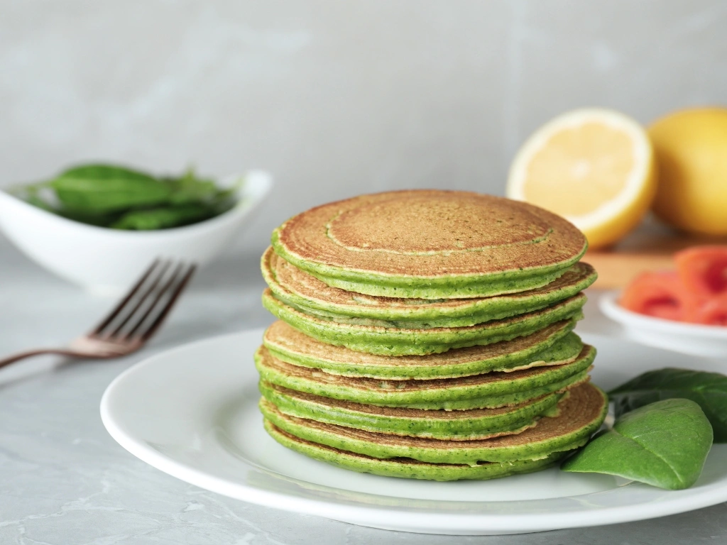 Stack of vibrant green matcha pancakes served on a white plate