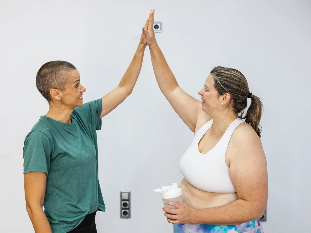  Personal trainer and nutritionist giving high five to client after successful workout