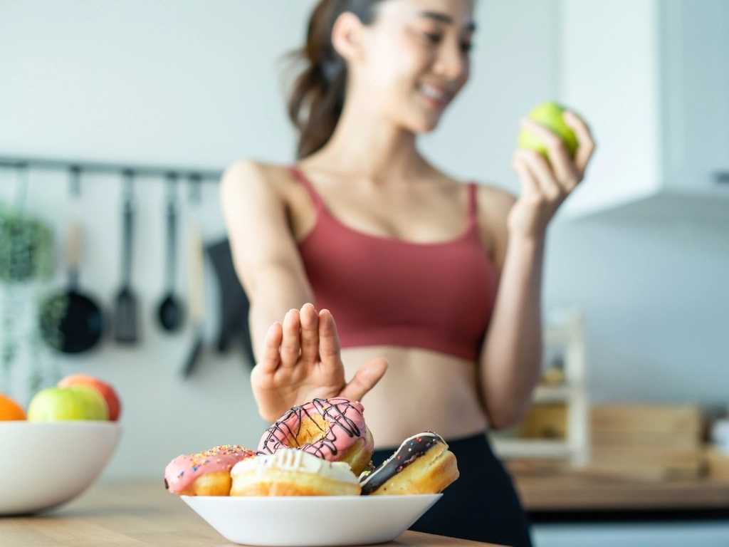 Woman in sportswear desire to chose fruit and ignore sweet donut enjoy eat healthy food for health after exercise