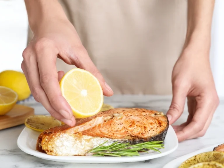 Person preparing a plate of salmon with lemon and rosemary