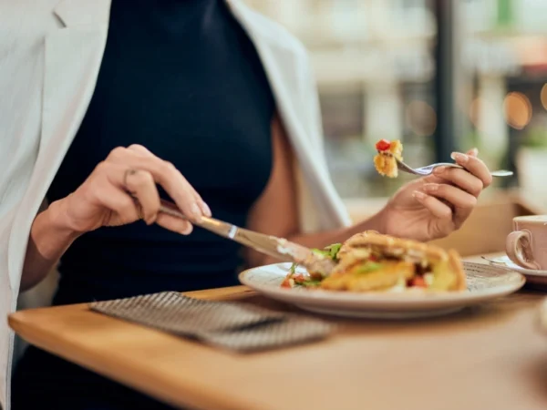 Woman holding a knife and fork, eating a meal