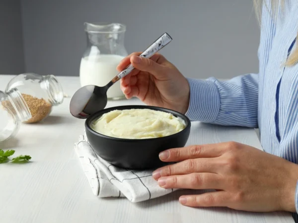 A woman eating a bowl of mashed potatoes with a spoon
