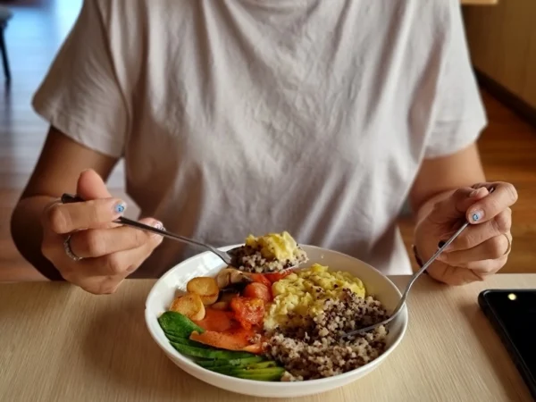 Person eating a hearty plate of quinoa, avocado, scrambled eggs, and other key staples of a healthy, energetic diet