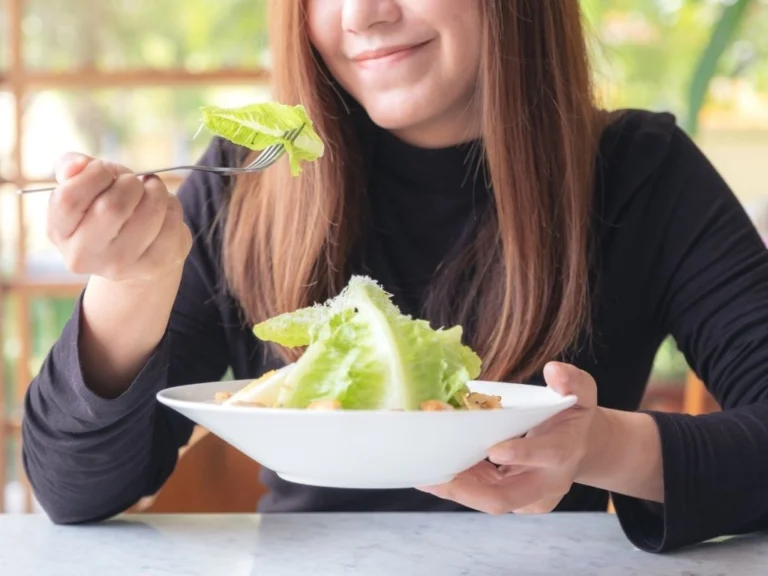 A woman enjoying a bowl of fresh leafy green salad