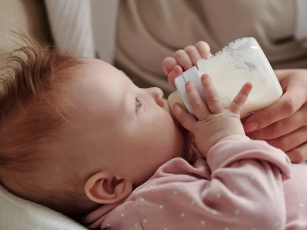 Parent gently holding a bottle to feed a baby with milk