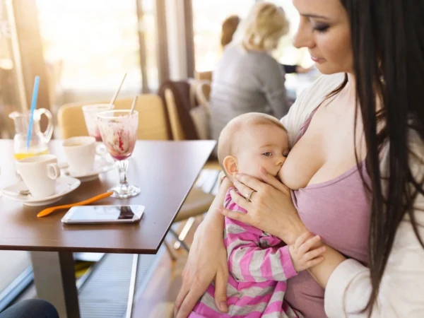 Mother breastfeeding her infant baby while sitting at a café table