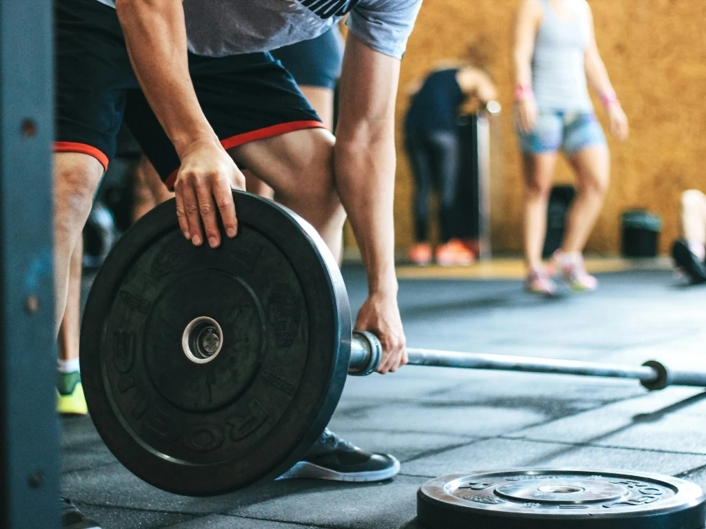 A person putting a black plate into a barbell sleeve