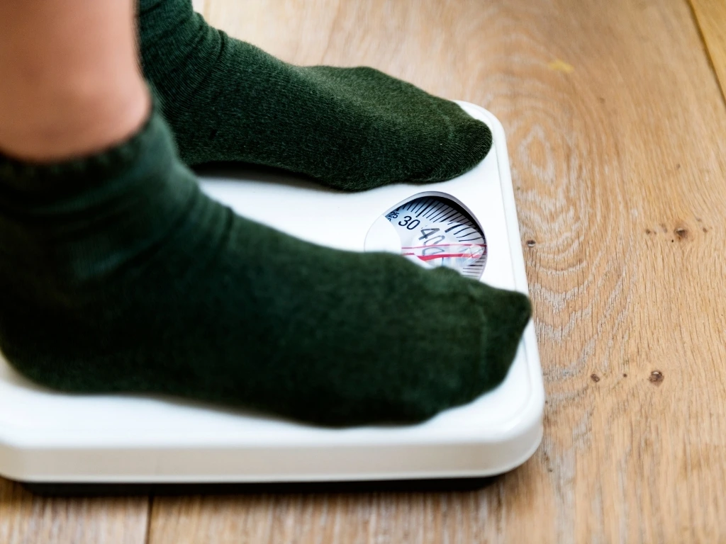 Person wearing green socks checking their weight on a scale