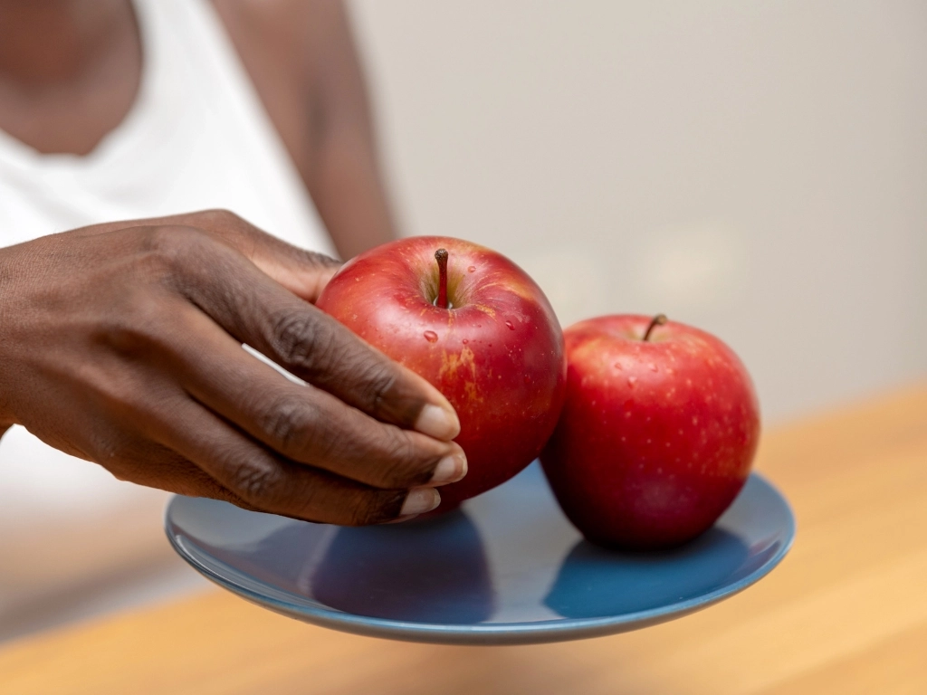 Woman holding a plate of two apples, taking one