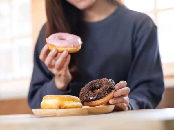 Closeup image of a young woman holding and enjoyed eating donuts at home