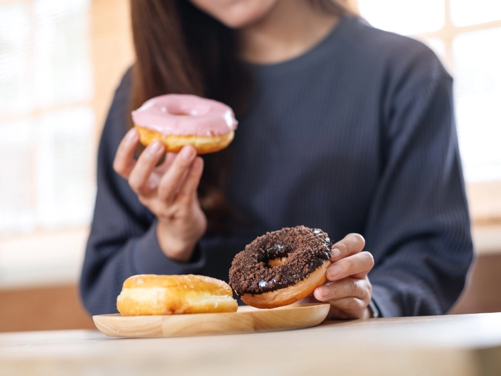 Closeup image of a young woman holding and enjoyed eating donuts at home