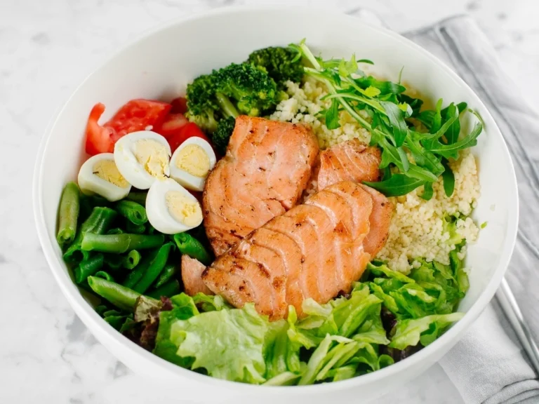 Bowl with salmon, quinoa, broccoli, eggs, and leafy greens