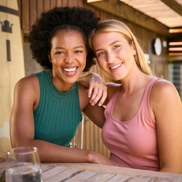 Two Happy Women Posing at Outdoor Wooden Table